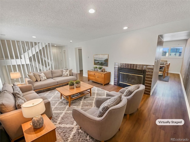 living room with wood-type flooring, a brick fireplace, and a textured ceiling