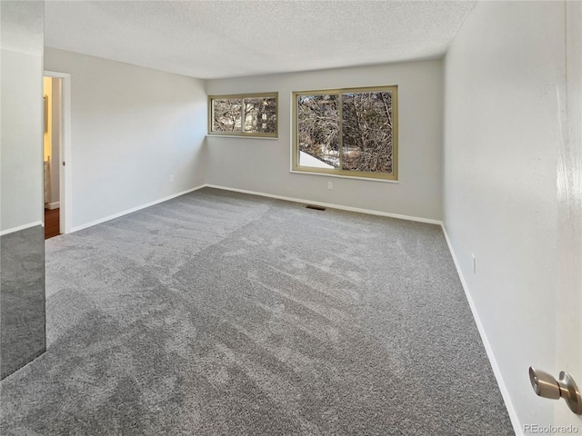 carpeted empty room featuring a textured ceiling