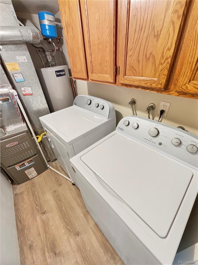 laundry area with cabinets, light hardwood / wood-style flooring, water heater, and washing machine and clothes dryer