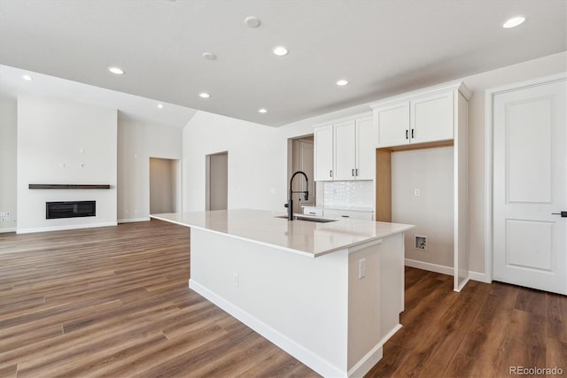 kitchen with white cabinetry, a large island, sink, dark wood-type flooring, and backsplash