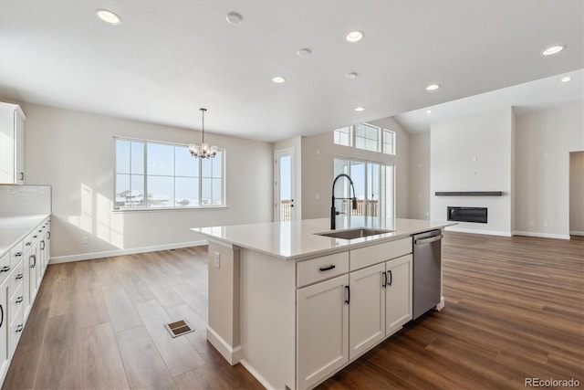 kitchen featuring sink, a center island with sink, dishwasher, a chandelier, and white cabinetry