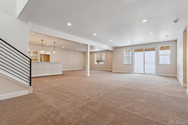 unfurnished living room with light carpet and a wealth of natural light