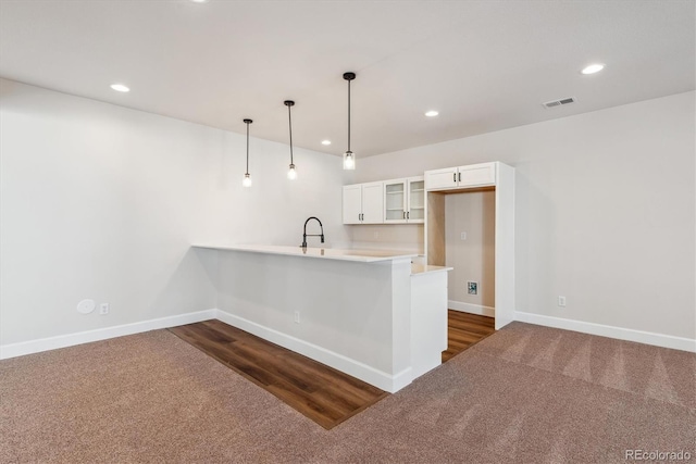 kitchen featuring dark carpet, kitchen peninsula, decorative light fixtures, and white cabinetry