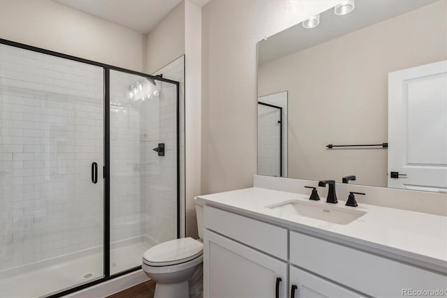 bathroom with an enclosed shower, vanity, and toilet