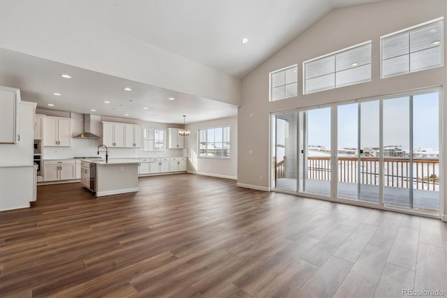 unfurnished living room with high vaulted ceiling, an inviting chandelier, dark wood-type flooring, and sink