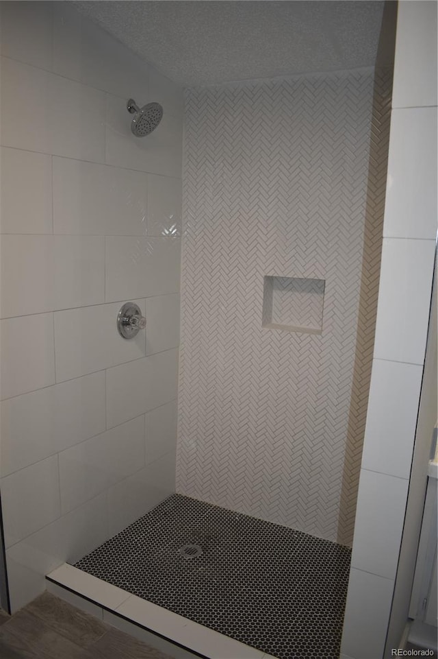 full bath with a textured ceiling and a tile shower