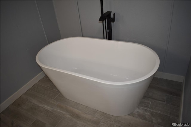 details with a soaking tub, a decorative wall, and baseboards