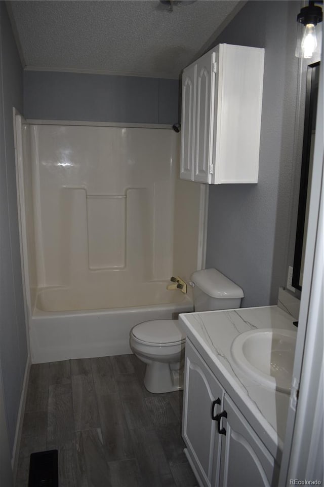 full bathroom featuring vanity, toilet, a textured ceiling, washtub / shower combination, and wood finished floors
