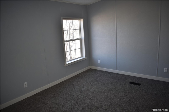 spare room with baseboards, dark colored carpet, and visible vents