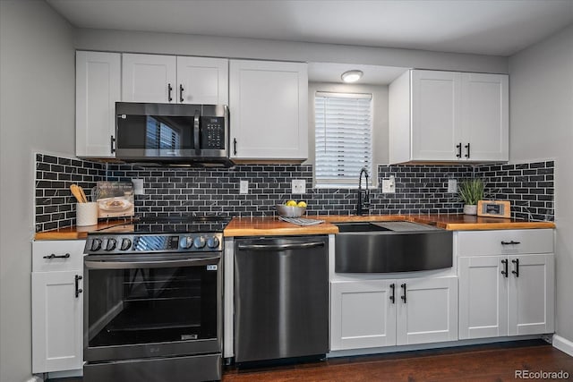 kitchen featuring wood counters, backsplash, stainless steel appliances, white cabinets, and dark hardwood / wood-style floors