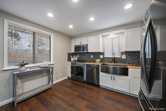 kitchen featuring appliances with stainless steel finishes, dark wood-type flooring, sink, white cabinets, and butcher block countertops