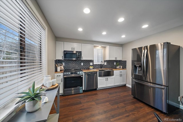 kitchen with dark wood-type flooring, sink, tasteful backsplash, white cabinetry, and stainless steel appliances