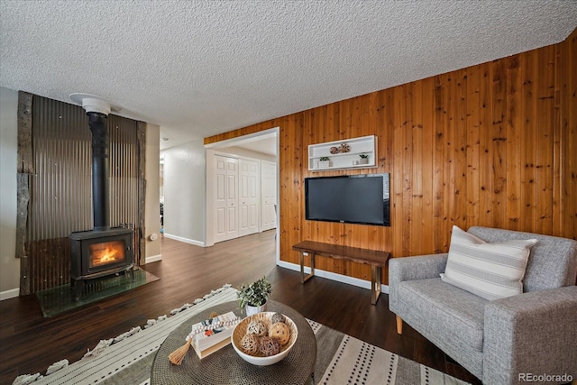 living room with dark hardwood / wood-style floors, a wood stove, and wooden walls