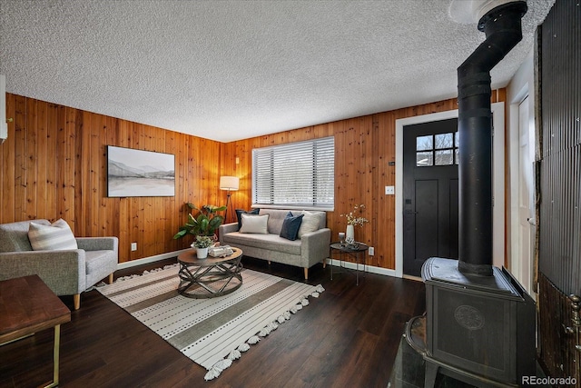 living room featuring a wood stove, wood walls, hardwood / wood-style floors, and a textured ceiling