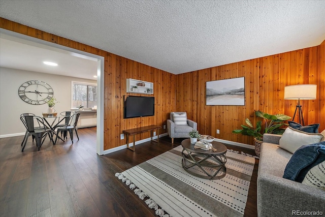 living room featuring a textured ceiling, dark hardwood / wood-style floors, and wooden walls