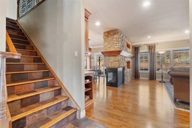 stairs with crown molding, a fireplace, and hardwood / wood-style flooring