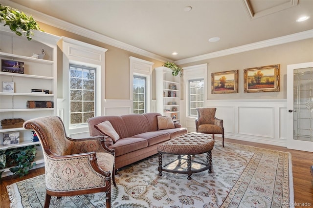 living room with built in shelves, hardwood / wood-style flooring, and crown molding