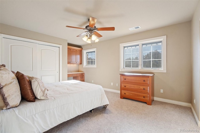 bedroom with ceiling fan, a closet, and light carpet