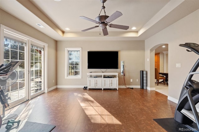 living room with a tray ceiling and ceiling fan