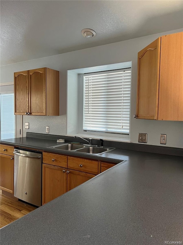 kitchen featuring sink, stainless steel dishwasher, a textured ceiling, and light wood-type flooring