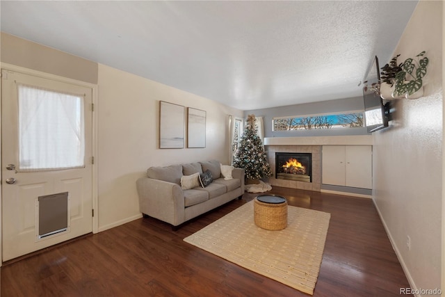 living room with dark hardwood / wood-style floors, a textured ceiling, and a tiled fireplace