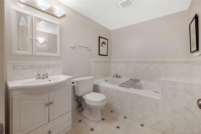 bathroom with tiled bath, vanity, and toilet