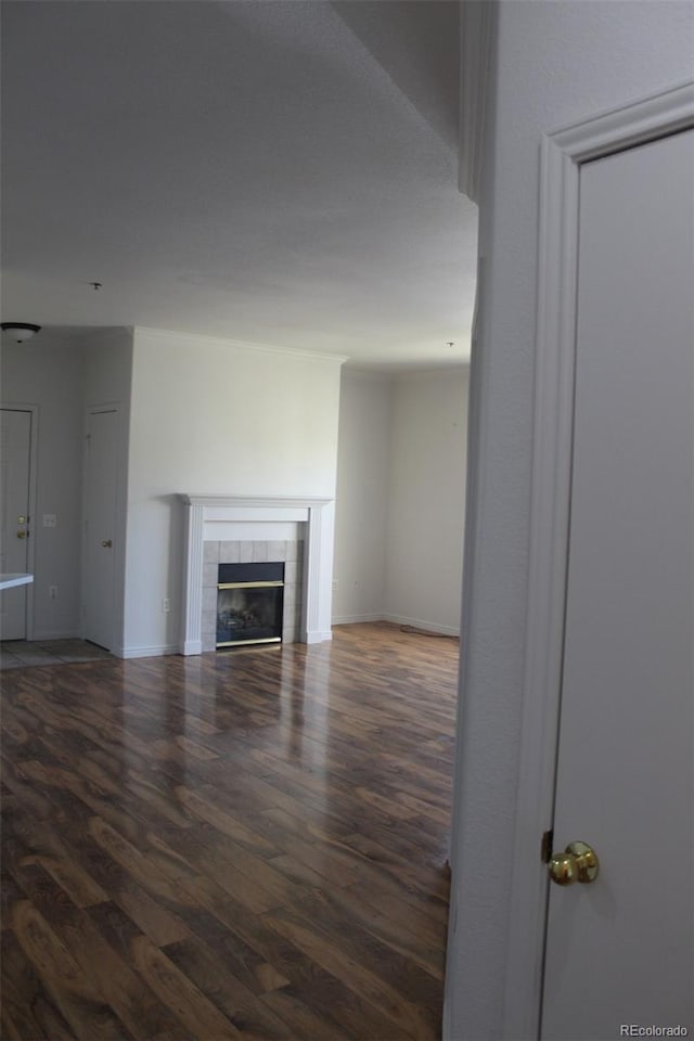 unfurnished living room with dark wood-type flooring and a tiled fireplace