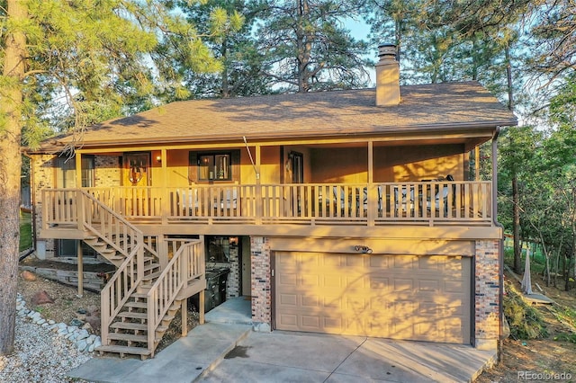 view of front facade with a garage, a chimney, brick siding, concrete driveway, and a porch