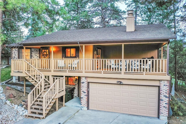 view of front of property with a garage, a chimney, a shingled roof, driveway, and covered porch