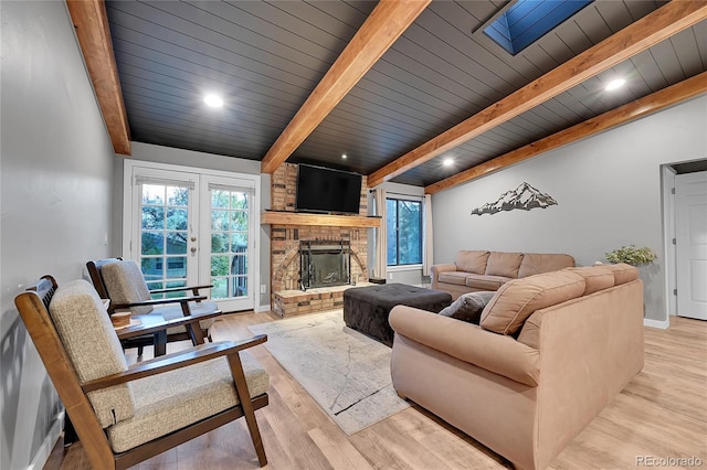 living area featuring beam ceiling, a large fireplace, plenty of natural light, wood finished floors, and wood ceiling