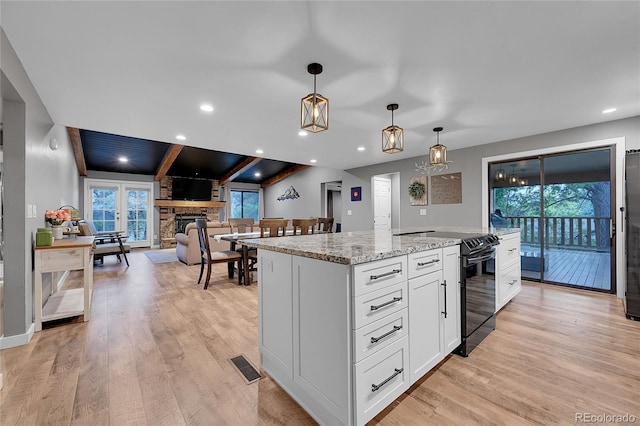 kitchen featuring black electric range, healthy amount of natural light, white cabinetry, light stone countertops, and recessed lighting