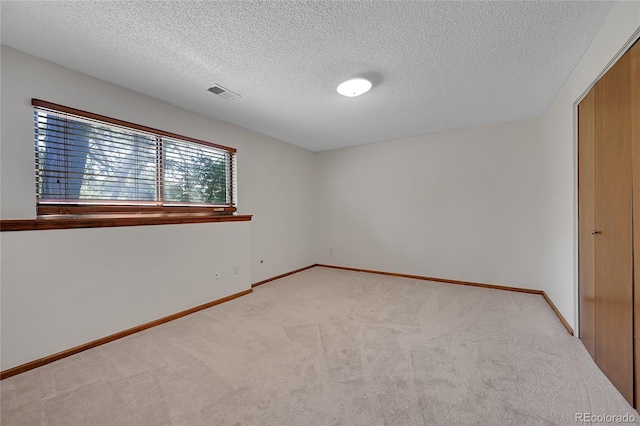 unfurnished room with light carpet, a textured ceiling, and baseboards