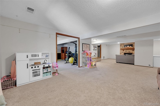 recreation room featuring carpet floors, a fireplace, and a textured ceiling
