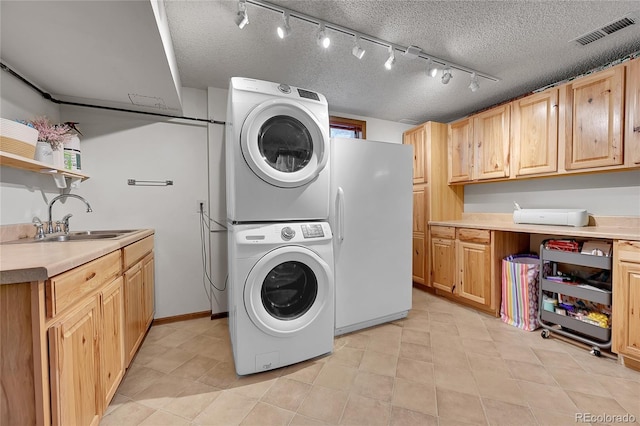 washroom featuring estacked washer and dryer, a textured ceiling, and light tile patterned floors