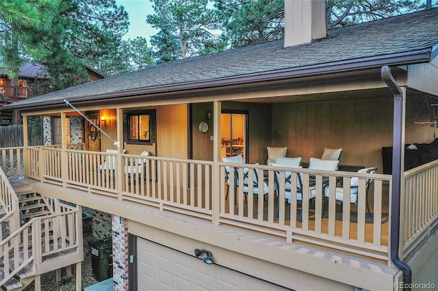 back of property with a garage, a chimney, and a shingled roof
