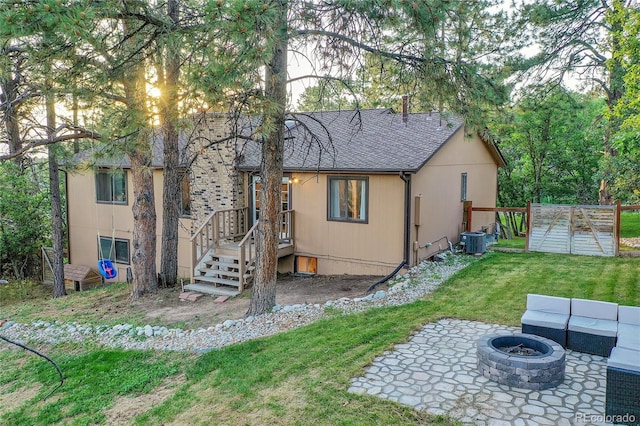 back of house with a fire pit, central air condition unit, a yard, a patio, and a shingled roof