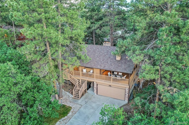 view of front of property with concrete driveway, an attached garage, roof with shingles, stairway, and a chimney