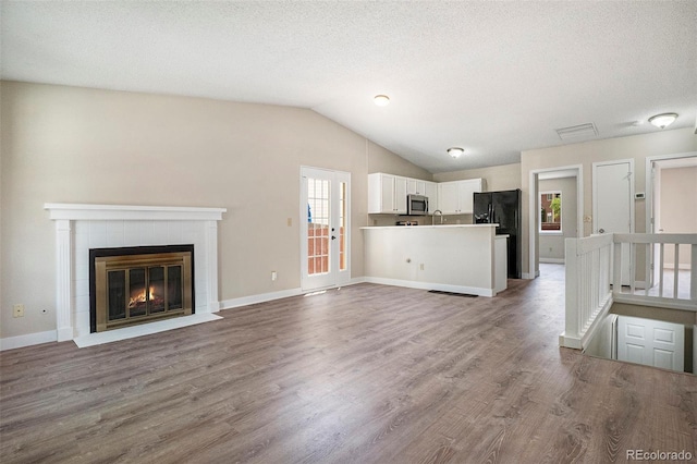8401 Sandreed Cir, Parker, CO 80134 - unfurnished living room with lofted ceiling, wood finished floors, a tile fireplace, and a textured ceiling