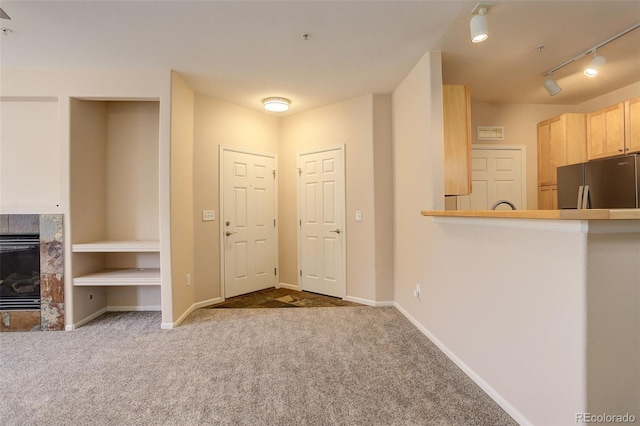 unfurnished living room with a premium fireplace, carpet flooring, and rail lighting