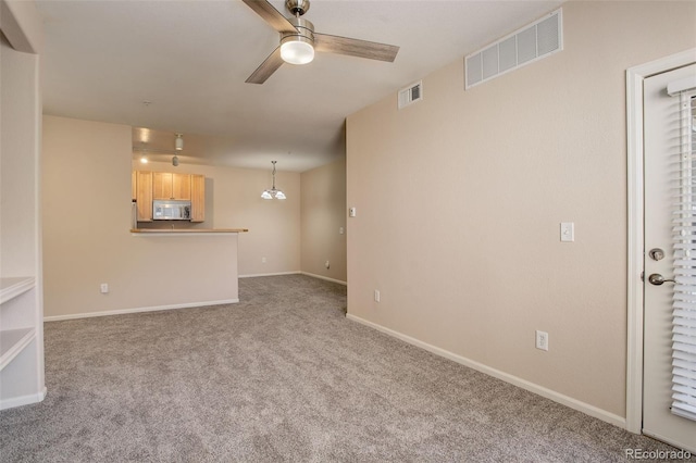 unfurnished living room featuring ceiling fan with notable chandelier and carpet flooring