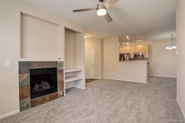 living room with a tiled fireplace, ceiling fan, and light colored carpet