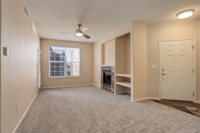 unfurnished living room with a tile fireplace, carpet flooring, and ceiling fan