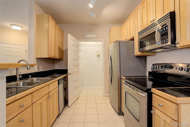 kitchen featuring light brown cabinetry, light tile patterned flooring, stainless steel appliances, and sink