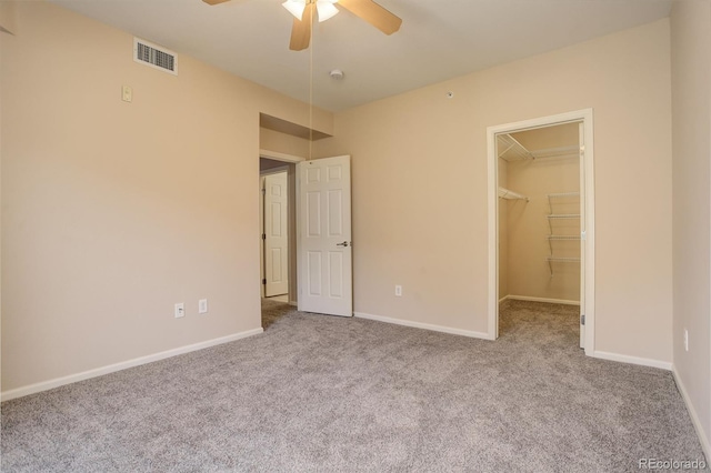 unfurnished bedroom with ceiling fan, a closet, light carpet, and a spacious closet