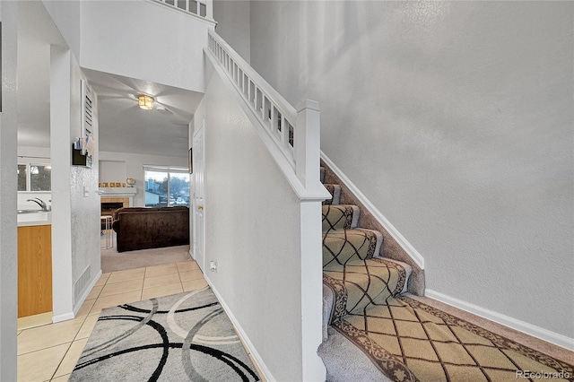 stairway with tile patterned floors, sink, and a tiled fireplace