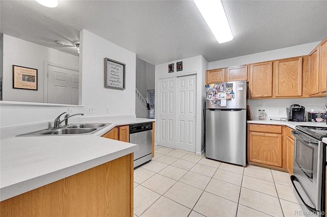 kitchen with a textured ceiling, light tile patterned floors, sink, and appliances with stainless steel finishes