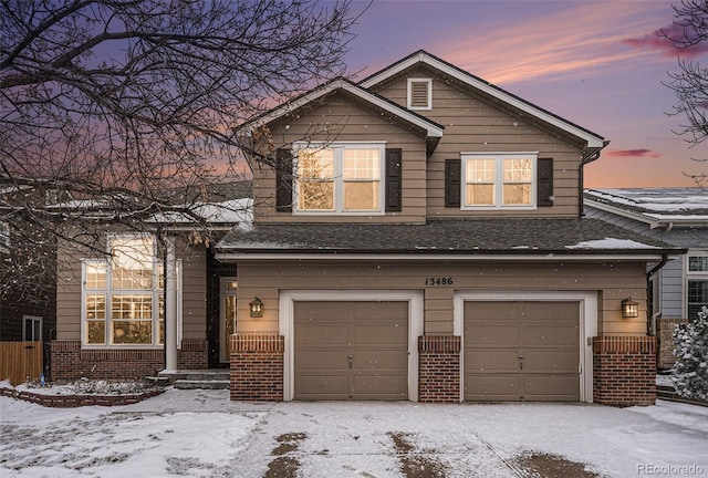 view of front facade featuring a shingled roof, brick siding, and an attached garage