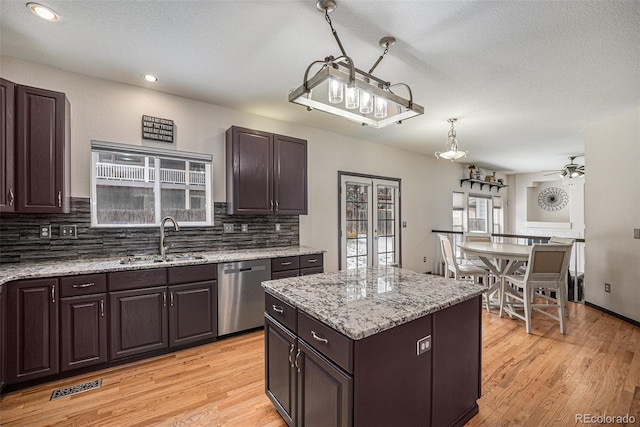 kitchen featuring dark brown cabinetry, stainless steel dishwasher, decorative light fixtures, a center island, and sink