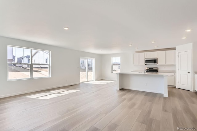 unfurnished living room with light wood-style flooring, recessed lighting, and baseboards