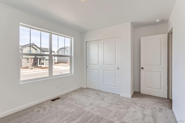 unfurnished bedroom featuring visible vents, baseboards, and carpet